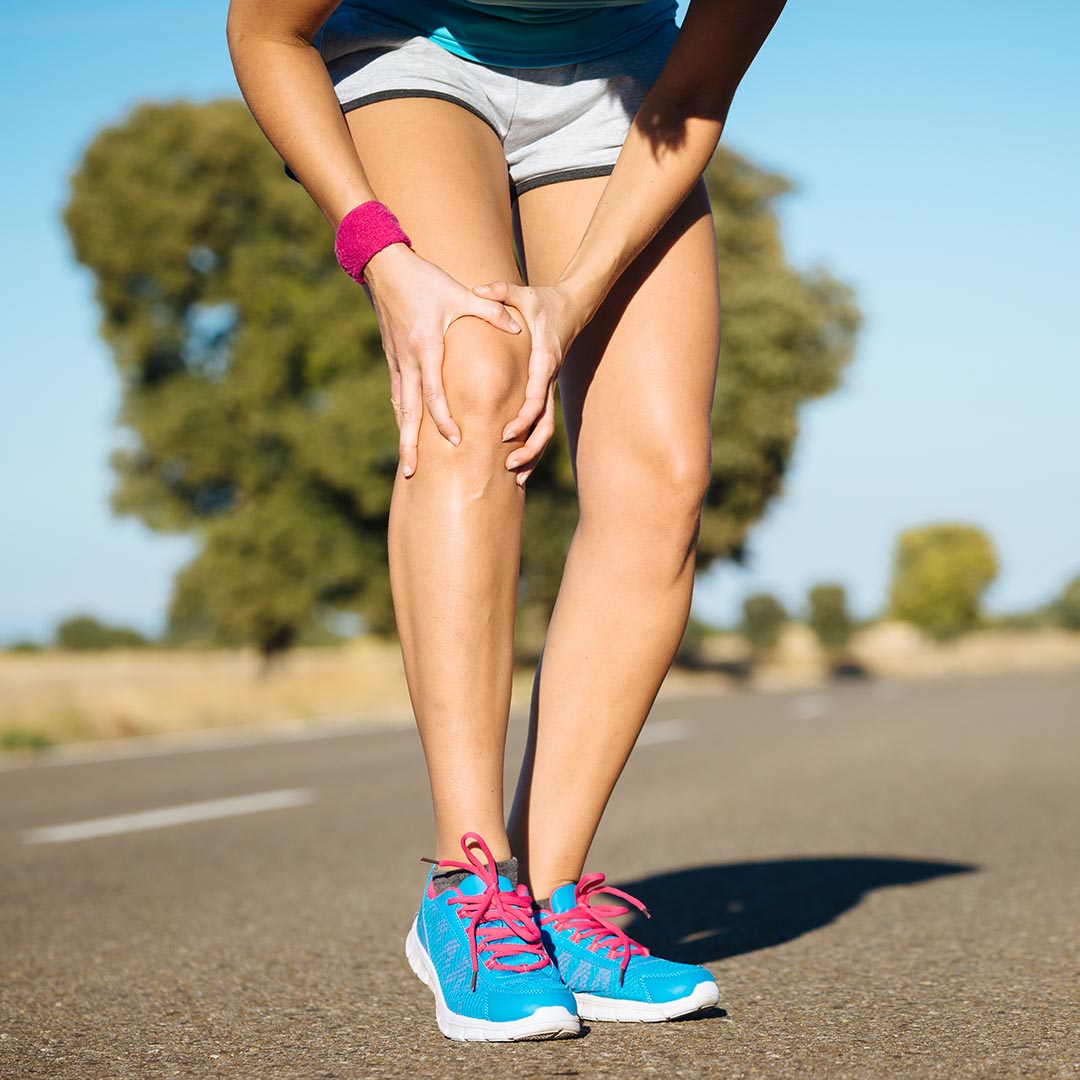 Athletic woman holding her knee in pain